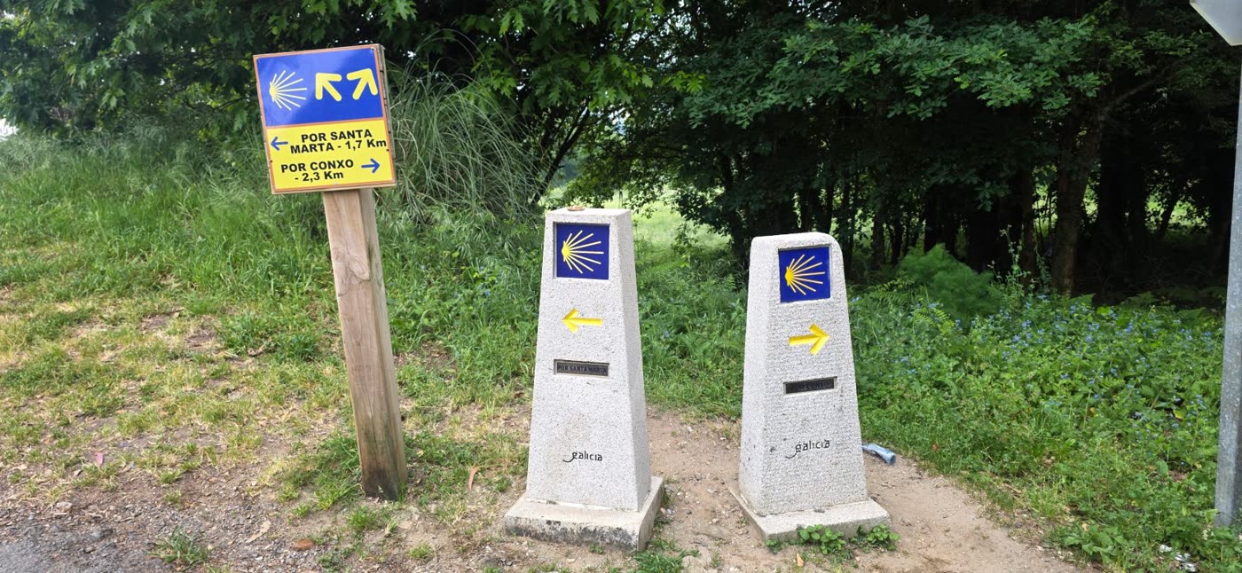 Two Galicia waymarkers at a fork in the road